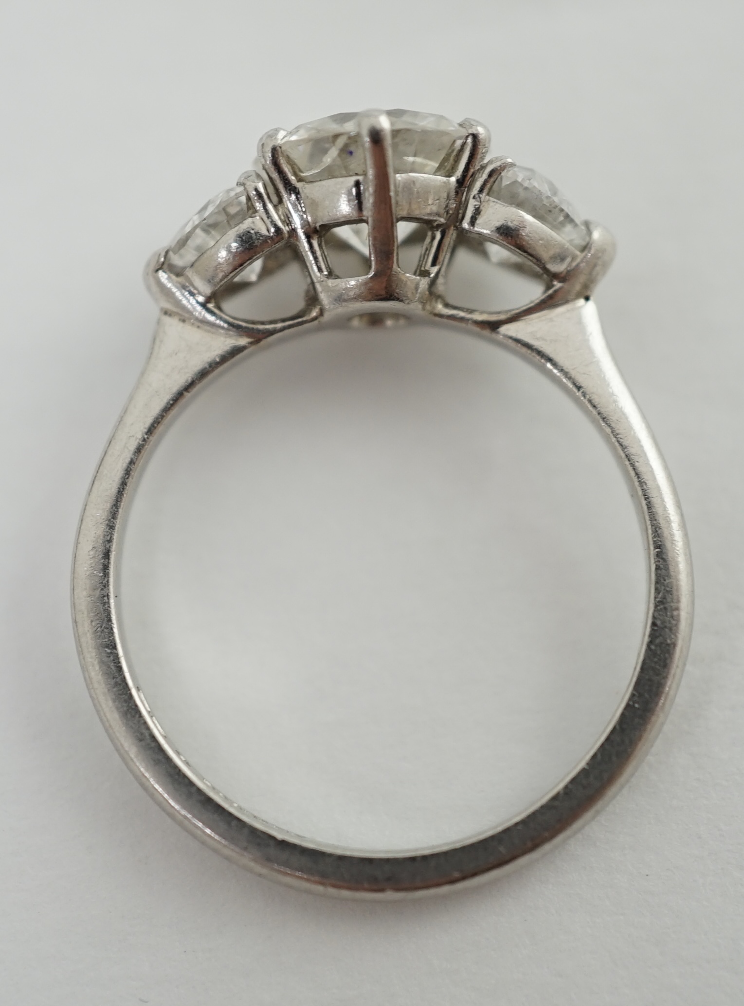 A modern platinum and single stone diamond ring, with two stone heart shaped diamond set shoulders